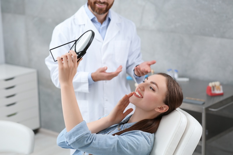 Young woman looking at her new CEREC dental crowns in Florence, KY & Tri-State area