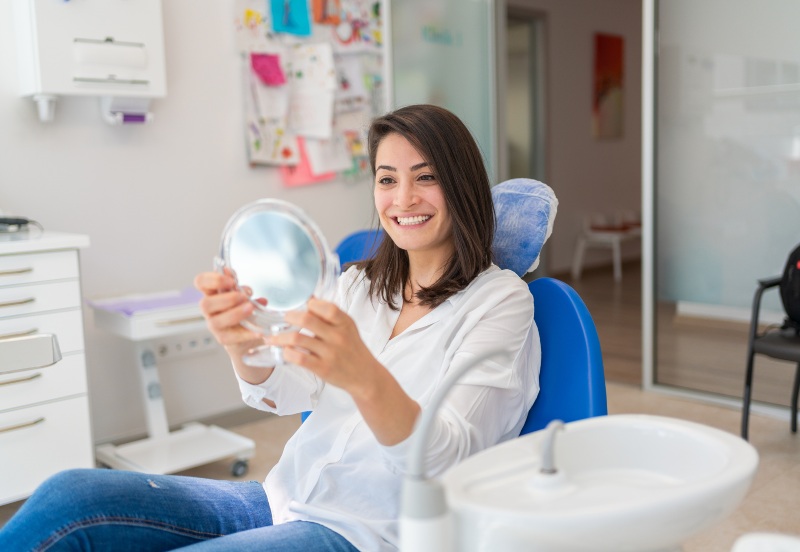 Woman checking her teeth after getting a temporary dental filling in Florence, KY & Tri-State area